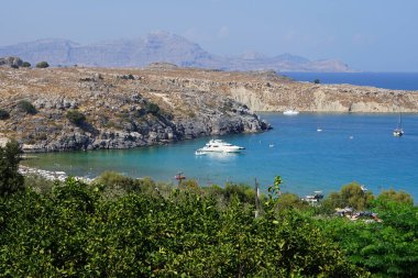 Ağustosta Lindos plajı manzarası. Lindos, Yunanistan 'ın Dodecanese kentindeki Rodos adasında bir arkeolojik alan, bir balıkçı köyü ve eski bir belediyedir.. 