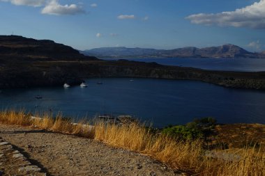 Ağustosta Lindos sahili manzarası. Lindos, Yunanistan 'ın Dodecanese kentindeki Rodos adasında bir arkeolojik alan, bir balıkçı köyü ve eski bir belediyedir..                                