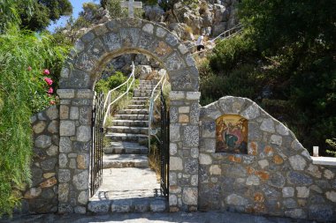 Pefkos veya Pefki, Rodos adası, Yunanistan - 28 Ağustos 2022: Peygamber Elias 'ı resmeden bir mozaik içeren bir kapı Peygamber Elias Kilisesi' nin merdivenlerinin önünde yer almaktadır. Pefkos 'u gören kilisenin İ.Ö. 12. yüzyıldan kalma olduğu düşünülüyor..  