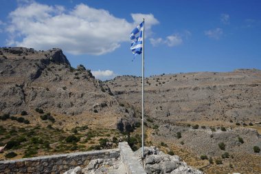 Yunan bayrağı Pefkos veya Pefki 'deki Elías Kilisesi' nin yakınlarındaki bir tepede dalgalanıyor. Yunanistan 'ın ulusal bayrağı resmi olarak ulusal sembollerinden biri olarak tanınıyor ve 5 eşit yatay mavi şeride sahip. Rodos Adası, Yunanistan