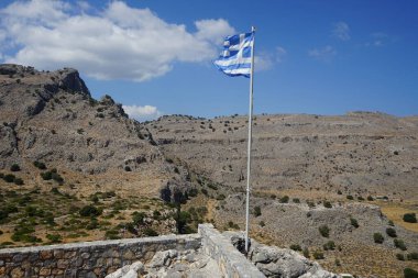 Yunan bayrağı Pefkos veya Pefki 'deki Elías Kilisesi' nin yakınlarındaki bir tepede dalgalanıyor. Yunanistan 'ın ulusal bayrağı resmi olarak ulusal sembollerinden biri olarak tanınıyor ve 5 eşit yatay mavi şeride sahip. Rodos Adası, Yunanistan