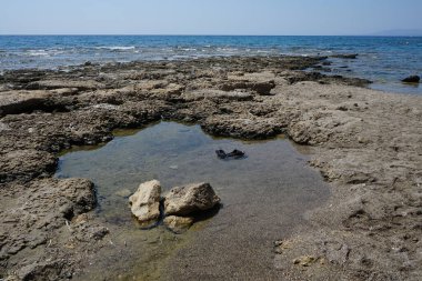 Pefki 'deki Akdeniz kıyısında sular çekildikten sonra plajda lastik parmak arası terlikler deniz suyunda yüzer. Pefkos ya da Pefki, Rhodes Adası 'nın doğu kıyısında bulunan ünlü bir sahil beldesidir. Pefkos veya Pefki, Rodos Adası, Yunanistan 