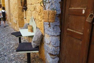 Bir masa ve iki sandalye, ortaçağ Rodos 'unda dar bir caddede kapalı bir evin yakınında yer alıyor. Rodos, Dodecanese Adasının eski bir belediyesidir. Rodos Şehri, Rodos Adası, Yunanistan