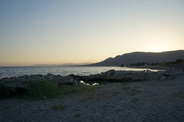 Ulusal park Katafigio Agrias Zois Xortis ile tepenin üzerinde gün batımı, bir Eylül akşamı Lardos 'ta Akdeniz kıyısına bakıyor. Lardos, Yunanistan 'ın Rodos adasının doğu kesiminde yer alan bir Yunan köyüdür.