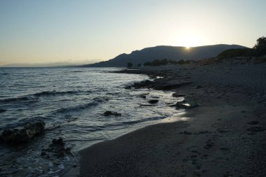 Ulusal park Katafigio Agrias Zois Xortis ile tepenin üzerinde gün batımı, bir Eylül akşamı Lardos 'ta Akdeniz kıyısına bakıyor. Lardos, Yunanistan 'ın Rodos adasının doğu kesiminde yer alan bir Yunan köyüdür. 