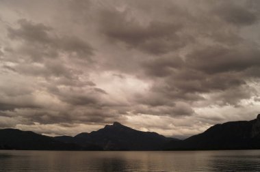 Mondsee Gölü 'nün çevresi bulutlu bir Eylül akşamı Alpler dağlarıyla çevrilidir. Mondsee, Salzkammergut 'un Yukarı Avusturya bölgesinde bulunan bir göldür. Avusturya 