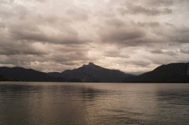 Mondsee Gölü 'nün çevresi bulutlu bir Eylül akşamı Alpler dağlarıyla çevrilidir. Mondsee, Salzkammergut 'un Yukarı Avusturya bölgesinde bulunan bir göldür. Avusturya 
