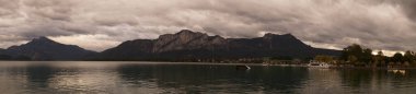 Fotoğraf panoraması. Mondsee Gölü 'nün çevresi bulutlu bir Eylül akşamı Alpler dağlarıyla çevrilidir. Mondsee, Salzkammergut 'un Yukarı Avusturya bölgesinde bulunan bir göldür. Avusturya