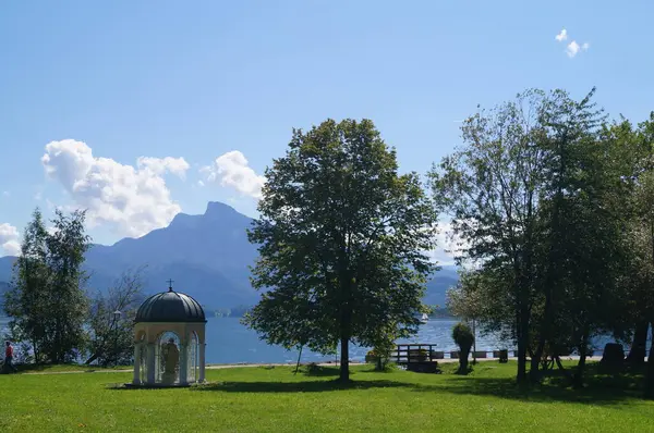 Mondsee 'deki göl kenarındaki manzarada Mondsee arka planda. Judas Thaddaeus Şapeli resimde solda görülebilir. Mondsee kasabası, Avusturya