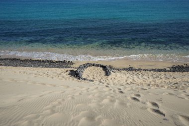Playa de Esquinzo, Esquinzo 'daki Esquinzo sahiline istiflenmiş taşlar, Atlantik Okyanusu yakınlarındaki turistleri rüzgara karşı korur. Esquinzo, Fuerteventura, Las Palmas, Kanarya Adaları, İspanya.