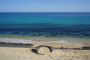 Playa de Esquinzo, Esquinzo 'daki Esquinzo sahiline istiflenmiş taşlar, Atlantik Okyanusu yakınlarındaki turistleri rüzgara karşı korur. Esquinzo, Fuerteventura, Las Palmas, Kanarya Adaları, İspanya.