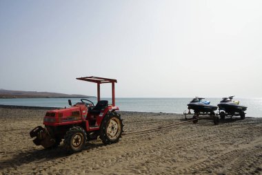 Costa Calma, Fuerteventura, İspanya - 22 Ekim 2022: Küçük bir MITSUBISHI MT20 traktörü Atlantik Okyanusu 'ndan Matas Körfezi kıyısına iki jet ski çıkardı. Las Palmas, Kanarya Adaları.