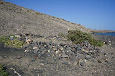 Matas Körfezi 'ndeki Atlantik Okyanusu yakınlarındaki Playas de Matas Blancas plajında istiflenmiş taşlar turistleri rüzgardan korur. Costa Calma, Fuerteventura, Las Palmas, Kanarya Adaları, İspanya.