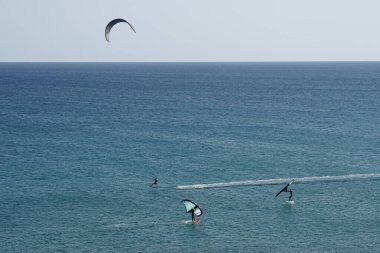 Matas Körfezi 'nde Atlantik Okyanusu' nun dalgalarında sörf tahtalarına binen bir uçurtma sörfçüsü ve kanat folyosu. Uçurtma sörfü ya da uçurtma uçurmak rüzgar enerjisi gerektiren bir spordur. Costa Calma, Fuerteventura, Las Palmas, İspanya.