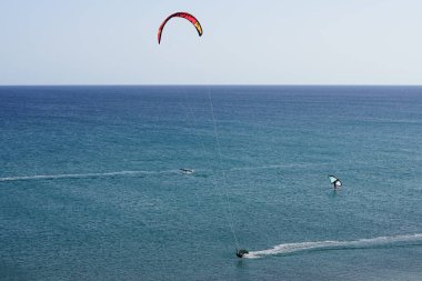 Matas Körfezi 'nde Atlantik Okyanusu' nun dalgalarında sörf tahtalarına binen bir uçurtma sörfçüsü ve kanat folyosu. Uçurtma sörfü ya da uçurtma uçurmak rüzgar enerjisi gerektiren bir spordur. Costa Calma, Fuerteventura, Las Palmas, İspanya.