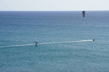 Matas Körfezi 'nde Atlantik Okyanusu' nun dalgalarında sörf tahtalarına binen bir uçurtma sörfçüsü ve bir kanat folyosu. Uçurtma sörfü ya da uçurtma uçurmak rüzgar enerjisi gerektiren bir spordur. Costa Calma, Fuerteventura, Las Palmas, İspanya. 