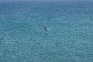 Bir kanat folyosu, Matas Körfezi 'ndeki Atlantik Okyanusu' nun dalgaları boyunca folyoyla yol alır. Kanat kanat çırpma, kanat çırpma veya kanat çırpma rüzgarı yakalamak için bir el kanadı kullanmayı ve suyun yüzeyinde bir levhayı itmeyi içerir. Costa Calma, İspanya. 