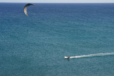 Bir uçurtma sörfçüsü, Matas Bay 'de, Matas de Blancas plajı boyunca sonbaharda Atlantik Okyanusu' nun dalgaları üzerinde sörf tahtasına biner. Uçurtma sörfü ya da uçurtma uçurmak rüzgar enerjisi gerektiren bir spordur. Costa Calma, Fuerteventura, Kanarya Adaları.