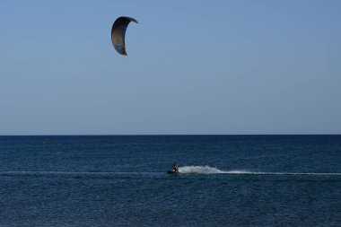 Bir uçurtma sörfçüsü, Matas Bay 'de, Matas de Blancas plajı boyunca sonbaharda Atlantik Okyanusu' nun dalgaları üzerinde sörf tahtasına biner. Uçurtma sörfü ya da uçurtma uçurmak rüzgar enerjisi gerektiren bir spordur. Costa Calma, Fuerteventura, Kanarya Adaları.