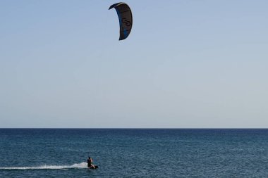 Bir uçurtma sörfçüsü, Matas Bay 'de, Matas de Blancas plajı boyunca sonbaharda Atlantik Okyanusu' nun dalgaları üzerinde sörf tahtasına biner. Uçurtma sörfü ya da uçurtma uçurmak rüzgar enerjisi gerektiren bir spordur. Costa Calma, Fuerteventura, Kanarya Adaları.