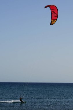 Bir uçurtma sörfçüsü, Matas Bay 'de, Matas de Blancas plajı boyunca sonbaharda Atlantik Okyanusu' nun dalgaları üzerinde sörf tahtasına biner. Uçurtma sörfü ya da uçurtma uçurmak rüzgar enerjisi gerektiren bir spordur. Costa Calma, Fuerteventura, Kanarya Adaları.
