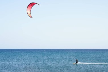 Bir uçurtma sörfçüsü, Matas Bay 'de, Matas de Blancas plajı boyunca sonbaharda Atlantik Okyanusu' nun dalgaları üzerinde sörf tahtasına biner. Uçurtma sörfü ya da uçurtma uçurmak rüzgar enerjisi gerektiren bir spordur. Costa Calma, Fuerteventura, Kanarya Adaları.