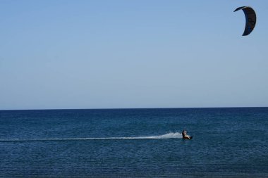 Bir uçurtma sörfçüsü, Matas Bay 'de, Matas de Blancas plajı boyunca sonbaharda Atlantik Okyanusu' nun dalgaları üzerinde sörf tahtasına biner. Uçurtma sörfü ya da uçurtma uçurmak rüzgar enerjisi gerektiren bir spordur. Costa Calma, Fuerteventura, Kanarya Adaları.