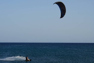 Bir uçurtma sörfçüsü, Matas Bay 'de, Matas de Blancas plajı boyunca sonbaharda Atlantik Okyanusu' nun dalgaları üzerinde sörf tahtasına biner. Uçurtma sörfü ya da uçurtma uçurmak rüzgar enerjisi gerektiren bir spordur. Costa Calma, Fuerteventura, Kanarya Adaları.