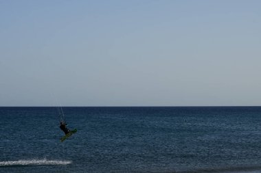 Bir uçurtma sörfçüsü, Matas Bay 'de, Matas de Blancas plajı boyunca sonbaharda Atlantik Okyanusu' nun dalgaları üzerinde sörf tahtasına biner. Uçurtma sörfü ya da uçurtma uçurmak rüzgar enerjisi gerektiren bir spordur. Costa Calma, Fuerteventura, Kanarya Adaları.