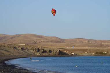Bir uçurtma sörfçüsü, Matas Bay 'de, Matas de Blancas plajı boyunca sonbaharda Atlantik Okyanusu' nun dalgaları üzerinde sörf tahtasına biner. Uçurtma sörfü ya da uçurtma uçurmak rüzgar enerjisi gerektiren bir spordur. Costa Calma, Fuerteventura, Kanarya Adaları.