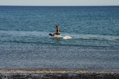 Bir uçurtma sörfçüsü, Matas Bay 'de, Matas de Blancas plajı boyunca sonbaharda Atlantik Okyanusu' nun dalgaları üzerinde sörf tahtasına biner. Uçurtma sörfü ya da uçurtma uçurmak rüzgar enerjisi gerektiren bir spordur. Costa Calma, Fuerteventura, Kanarya Adaları.