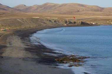 Bir uçurtma sörfçüsü, Matas Bay 'de, Matas de Blancas plajı boyunca sonbaharda Atlantik Okyanusu' nun dalgaları üzerinde sörf tahtasına biner. Uçurtma sörfü ya da uçurtma uçurmak rüzgar enerjisi gerektiren bir spordur. Costa Calma, Fuerteventura, Kanarya Adaları.
