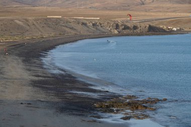 Bir uçurtma sörfçüsü, Matas Bay 'de, Matas de Blancas plajı boyunca sonbaharda Atlantik Okyanusu' nun dalgaları üzerinde sörf tahtasına biner. Uçurtma sörfü ya da uçurtma uçurmak rüzgar enerjisi gerektiren bir spordur. Costa Calma, Fuerteventura, Kanarya Adaları.