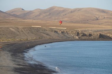 Bir uçurtma sörfçüsü, Matas Bay 'de, Matas de Blancas plajı boyunca sonbaharda Atlantik Okyanusu' nun dalgaları üzerinde sörf tahtasına biner. Uçurtma sörfü ya da uçurtma uçurmak rüzgar enerjisi gerektiren bir spordur. Costa Calma, Fuerteventura, Kanarya Adaları.