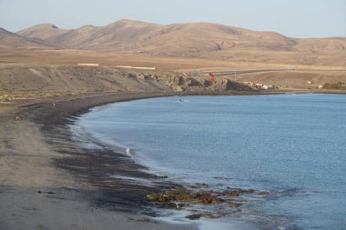 Bir uçurtma sörfçüsü, Matas Bay 'de, Matas de Blancas plajı boyunca sonbaharda Atlantik Okyanusu' nun dalgaları üzerinde sörf tahtasına biner. Uçurtma sörfü ya da uçurtma uçurmak rüzgar enerjisi gerektiren bir spordur. Costa Calma, Fuerteventura, Kanarya Adaları.