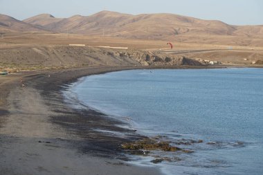 Bir uçurtma sörfçüsü, Matas Bay 'de, Matas de Blancas plajı boyunca sonbaharda Atlantik Okyanusu' nun dalgaları üzerinde sörf tahtasına biner. Uçurtma sörfü ya da uçurtma uçurmak rüzgar enerjisi gerektiren bir spordur. Costa Calma, Fuerteventura, Kanarya Adaları.