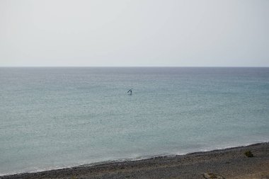 Bir kanat folyosu, Matas Körfezi 'ndeki Atlantik Okyanusu' nun dalgaları boyunca folyoyla yol alır. Kanat kanat çırpma, kanat çırpma veya kanat çırpma rüzgarı yakalamak için bir el kanadı kullanmayı ve suyun yüzeyinde bir levhayı itmeyi içerir. Costa Calma, İspanya. 