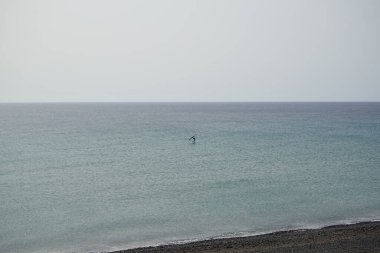 Bir kanat folyosu, Matas Körfezi 'ndeki Atlantik Okyanusu' nun dalgaları boyunca folyoyla yol alır. Kanat kanat çırpma, kanat çırpma veya kanat çırpma rüzgarı yakalamak için bir el kanadı kullanmayı ve suyun yüzeyinde bir levhayı itmeyi içerir. Costa Calma, İspanya. 