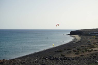 Matas Körfezi 'nde Atlantik Okyanusu' nun dalgalarında sörf tahtalarına binen bir uçurtma sörfçüsü ve kanat folyosu. Uçurtma sörfü ya da uçurtma uçurmak rüzgar enerjisi gerektiren bir spordur. Costa Calma, Fuerteventura, Las Palmas, İspanya. 
