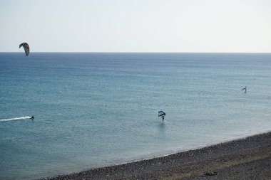 Matas Körfezi 'nde Atlantik Okyanusu' nun dalgalarında sörf tahtalarına binen bir uçurtma sörfçüsü ve kanat folyosu. Uçurtma sörfü ya da uçurtma uçurmak rüzgar enerjisi gerektiren bir spordur. Costa Calma, Fuerteventura, Las Palmas, İspanya. 