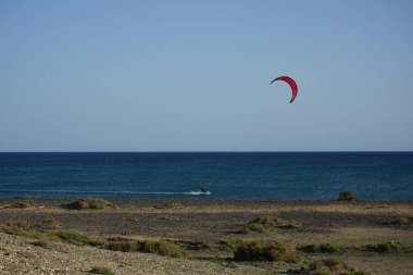 Bir uçurtma sörfçüsü, Matas Bay 'de, Matas de Blancas plajı boyunca sonbaharda Atlantik Okyanusu' nun dalgaları üzerinde sörf tahtasına biner. Uçurtma sörfü ya da uçurtma uçurmak rüzgar enerjisi gerektiren bir spordur. Costa Calma, Fuerteventura, Kanarya Adaları.  