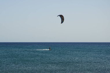 Bir uçurtma sörfçüsü, Matas Bay 'de, Matas de Blancas plajı boyunca sonbaharda Atlantik Okyanusu' nun dalgaları üzerinde sörf tahtasına biner. Uçurtma sörfü ya da uçurtma uçurmak rüzgar enerjisi gerektiren bir spordur. Costa Calma, Fuerteventura, Kanarya Adaları.  