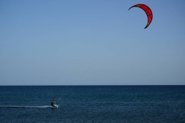 Bir uçurtma sörfçüsü, Matas Bay 'de, Matas de Blancas plajı boyunca sonbaharda Atlantik Okyanusu' nun dalgaları üzerinde sörf tahtasına biner. Uçurtma sörfü ya da uçurtma uçurmak rüzgar enerjisi gerektiren bir spordur. Costa Calma, Fuerteventura, Kanarya Adaları.  