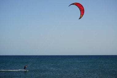 Bir uçurtma sörfçüsü, Matas Bay 'de, Matas de Blancas plajı boyunca sonbaharda Atlantik Okyanusu' nun dalgaları üzerinde sörf tahtasına biner. Uçurtma sörfü ya da uçurtma uçurmak rüzgar enerjisi gerektiren bir spordur. Costa Calma, Fuerteventura, Kanarya Adaları.  