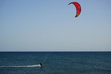 Bir uçurtma sörfçüsü, Matas Bay 'de, Matas de Blancas plajı boyunca sonbaharda Atlantik Okyanusu' nun dalgaları üzerinde sörf tahtasına biner. Uçurtma sörfü ya da uçurtma uçurmak rüzgar enerjisi gerektiren bir spordur. Costa Calma, Fuerteventura, Kanarya Adaları.  