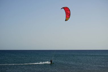 Bir uçurtma sörfçüsü, Matas Bay 'de, Matas de Blancas plajı boyunca sonbaharda Atlantik Okyanusu' nun dalgaları üzerinde sörf tahtasına biner. Uçurtma sörfü ya da uçurtma uçurmak rüzgar enerjisi gerektiren bir spordur. Costa Calma, Fuerteventura, Kanarya Adaları.  