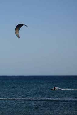 Bir uçurtma sörfçüsü, Matas Bay 'de, Matas de Blancas plajı boyunca sonbaharda Atlantik Okyanusu' nun dalgaları üzerinde sörf tahtasına biner. Uçurtma sörfü ya da uçurtma uçurmak rüzgar enerjisi gerektiren bir spordur. Costa Calma, Fuerteventura, Kanarya Adaları.  