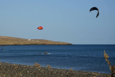 Kiteboardcular sörf tahtalarını Matas Körfezi 'ndeki Atlantik Okyanusu' nun dalgalarından geçiriyorlar. Uçurtma sörfü ya da uçurtma uçurmak rüzgar enerjisi gerektiren bir spordur. Costa Calma, Fuerteventura, Las Palmas, Kanarya Adaları, İspanya.  