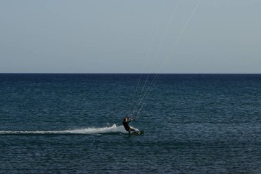 Bir uçurtma sörfçüsü, Matas Bay 'de, Matas de Blancas plajı boyunca sonbaharda Atlantik Okyanusu' nun dalgaları üzerinde sörf tahtasına biner. Uçurtma sörfü ya da uçurtma uçurmak rüzgar enerjisi gerektiren bir spordur. Costa Calma, Fuerteventura, Kanarya Adaları. 