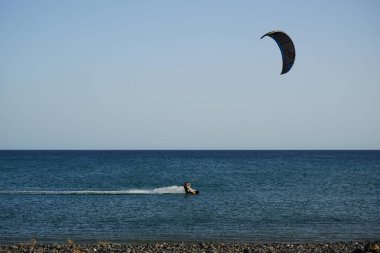 Bir uçurtma sörfçüsü, Matas Bay 'de, Matas de Blancas plajı boyunca sonbaharda Atlantik Okyanusu' nun dalgaları üzerinde sörf tahtasına biner. Uçurtma sörfü ya da uçurtma uçurmak rüzgar enerjisi gerektiren bir spordur. Costa Calma, Fuerteventura, Kanarya Adaları.  
